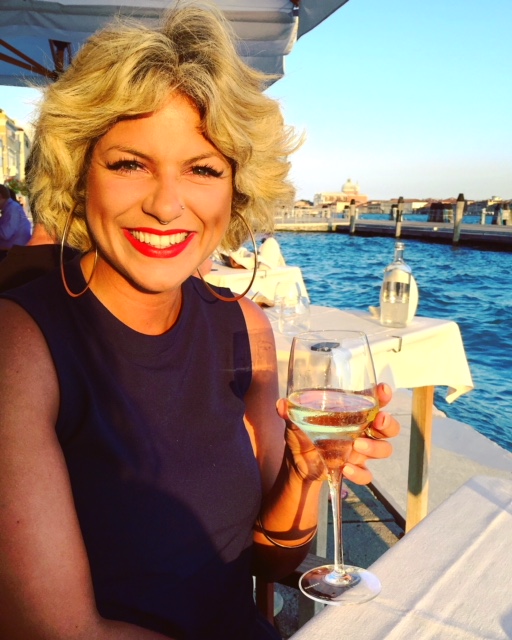 Woman holding glass of wine in front of harbour